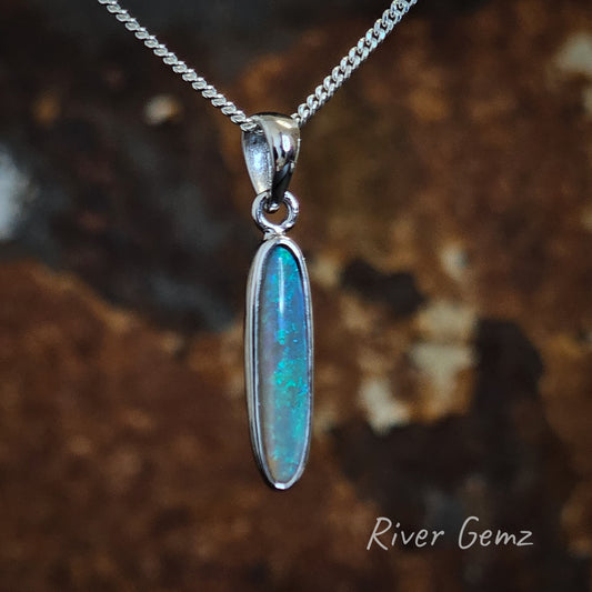 Long oval shaped blue and green crystal opal besel set in silver necklace with large bail.