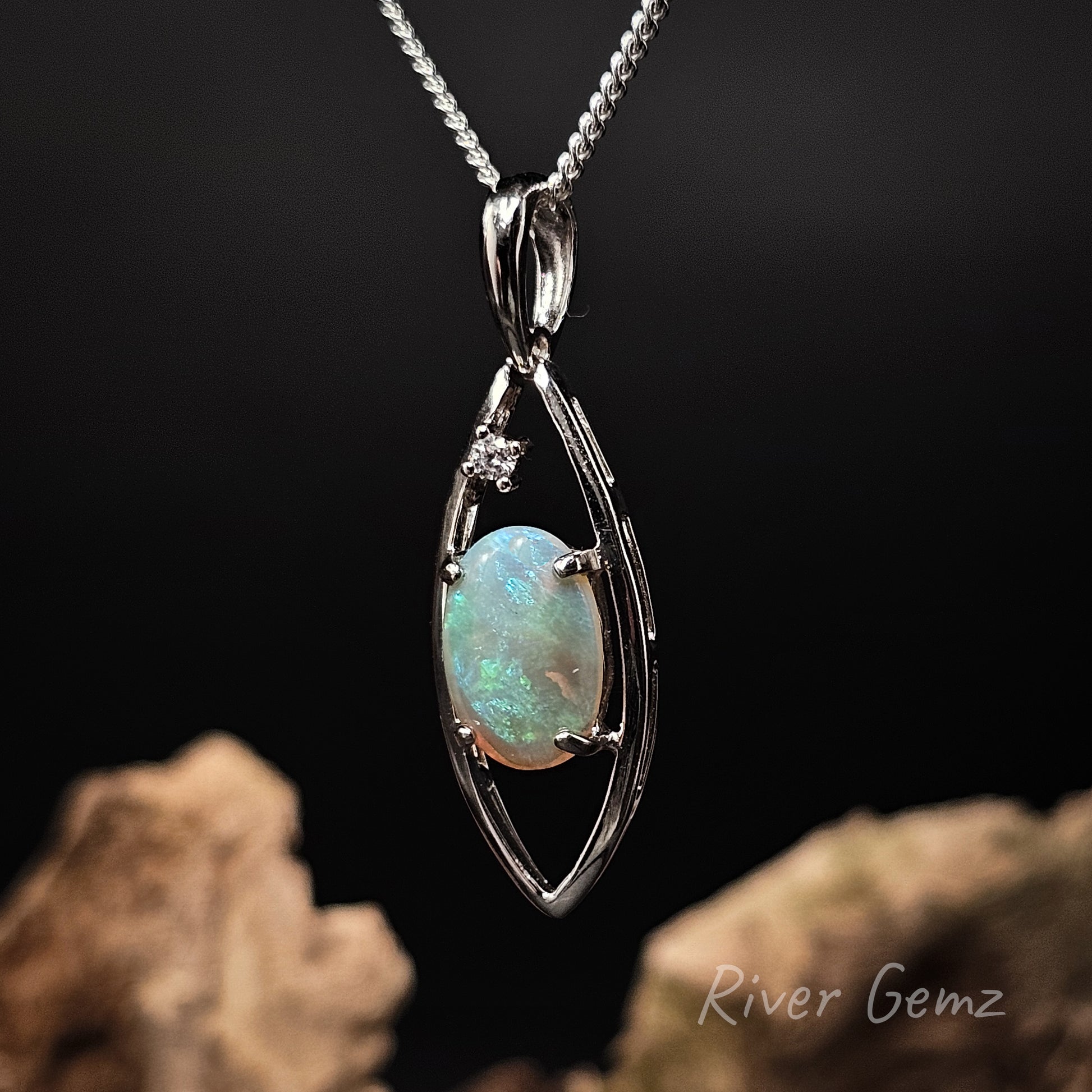 Silver pendant with a green crystal opal on a dark background, featuring 'River Gemz' branding.