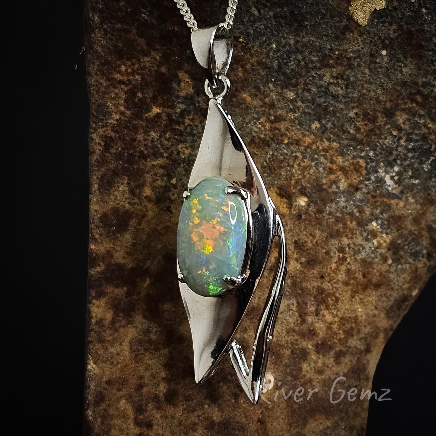 Oval shaped black opal claw set in a eucalyptus leaf shaped silver necklace with large bail.