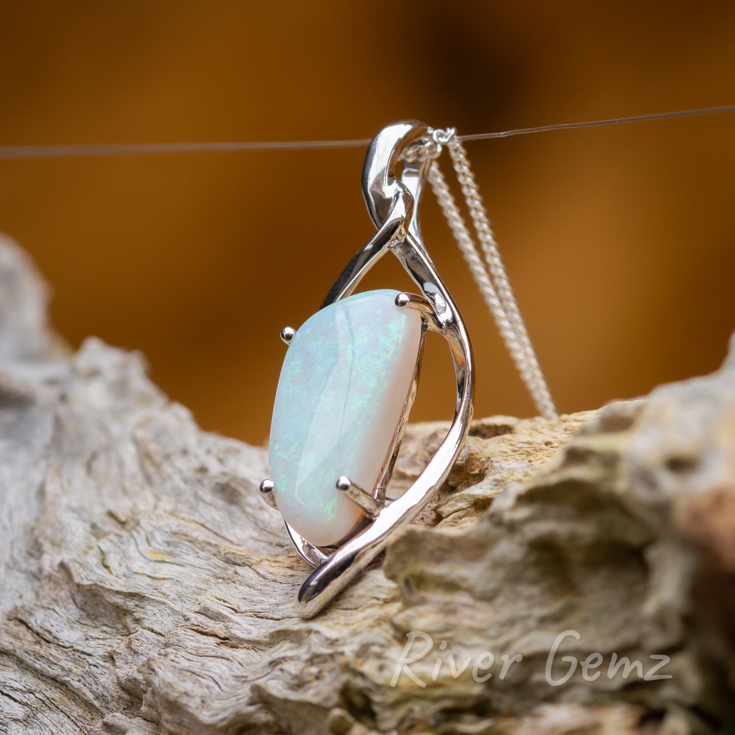 The stylish setting has cross-over arms that encompass the free-form cut opal secured by 4 claws. Bail is integrated in the pendant setting.