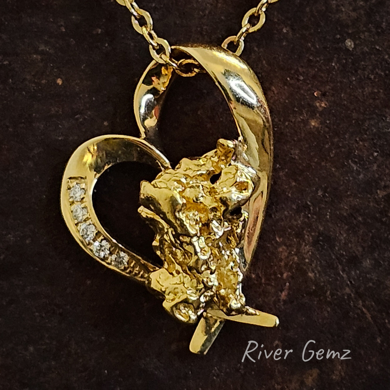 The outline of a gold heart with 5 diamonds in a row on the left of the heart's rim and a large nugget at the base of the pendant.