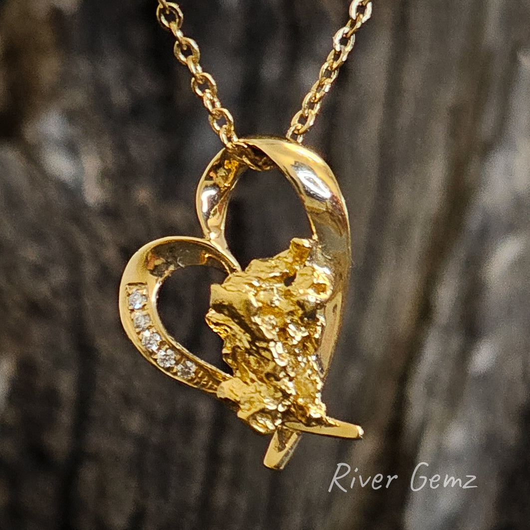 Heart shaped gold pendant with diamonds on the heart's rim and a large nugget at the base of the heart.