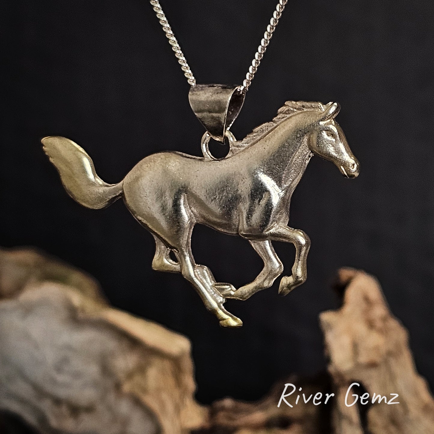 Silver horse pendant on a chain with a dark background.