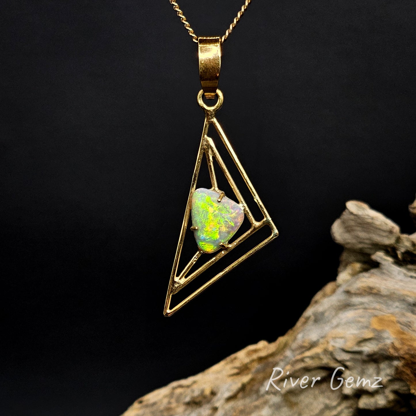 Triangle-shaped light opal claw set in yellow gold pendant.