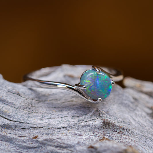 Oval shaped semi-black opal claw set in narrow shank of the white gold ring.