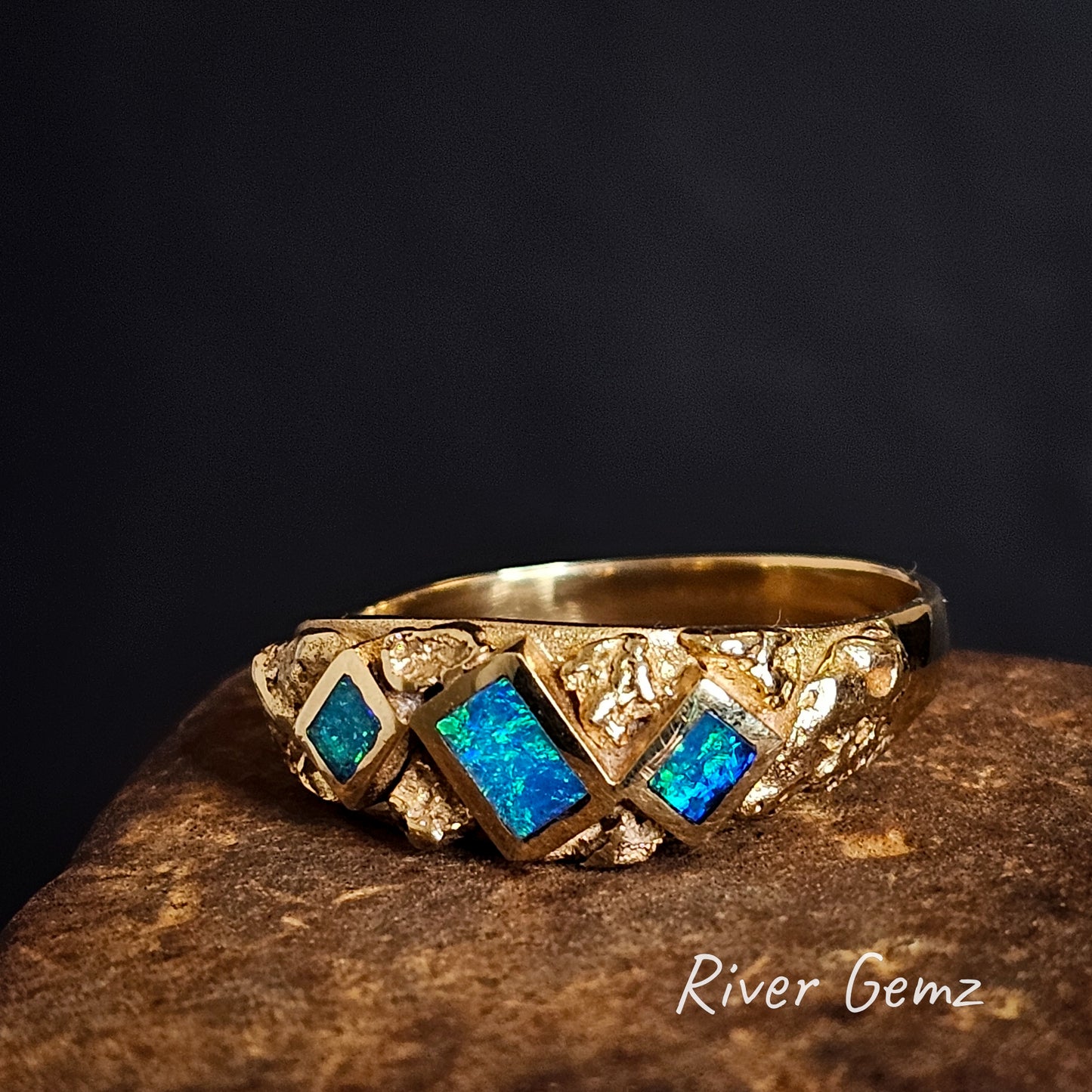 Gold ring with natural nuggets and 3 rectangular blue and green opals on a dark background, branded 'River Gemz'.