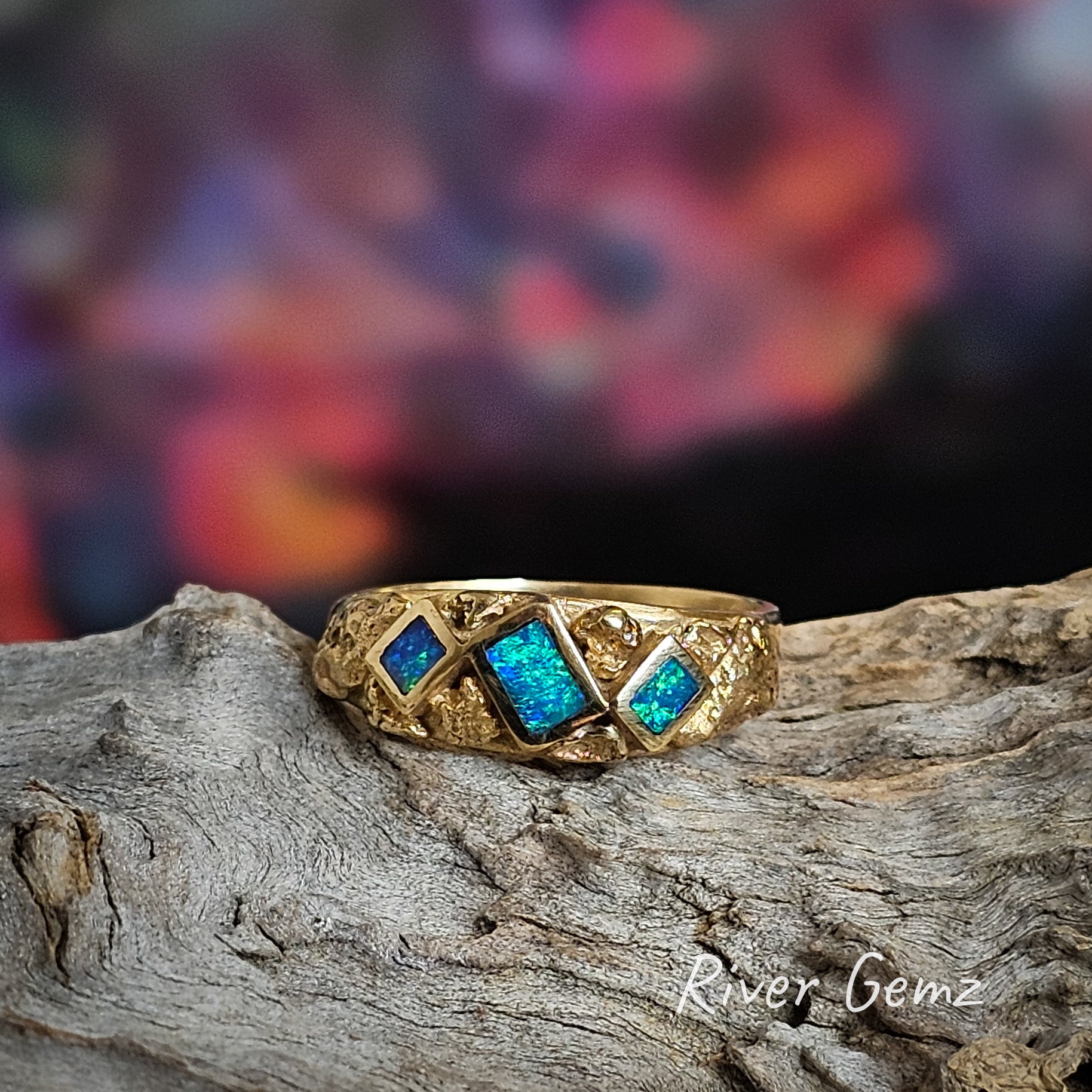 Three rectangular shaped dark opals set in yellow gold ring with natural nuggets around the opals.