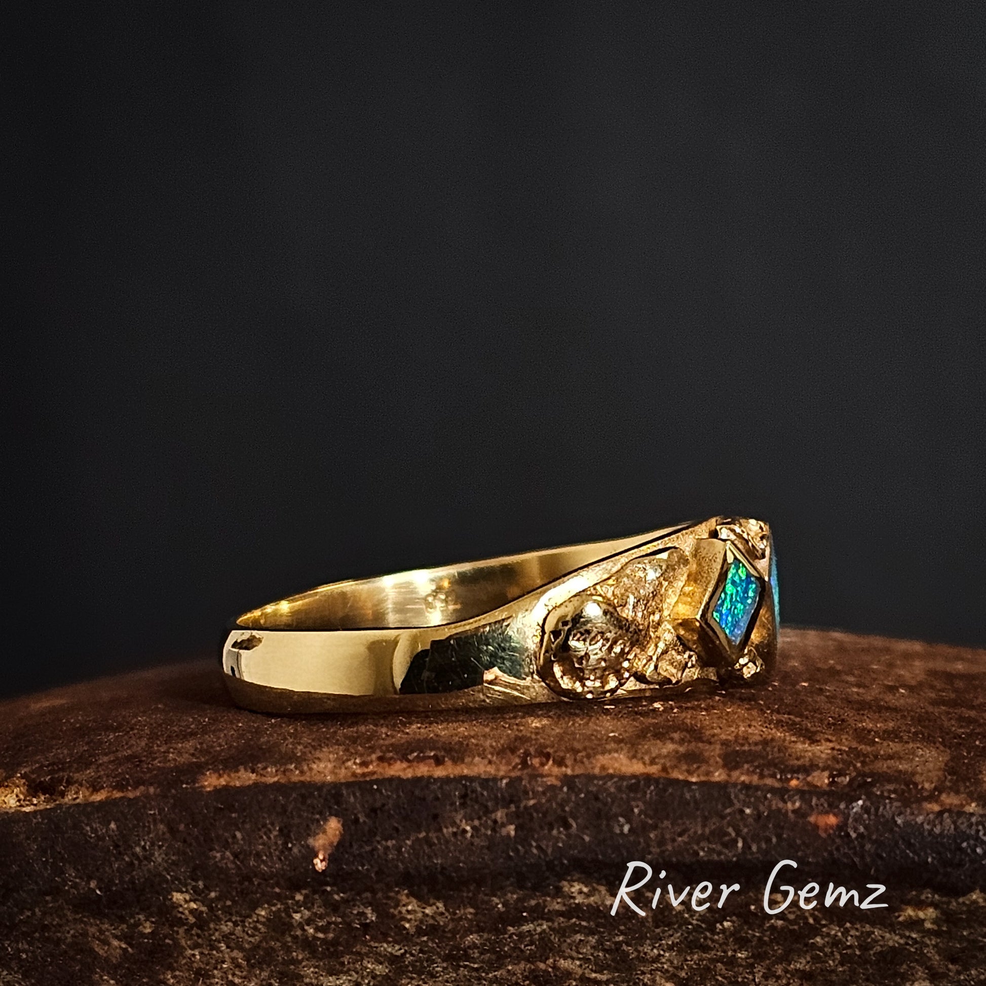 Side view of high grade gold ring with gemstone on a dark background, featuring the brand 'River Gemz'.