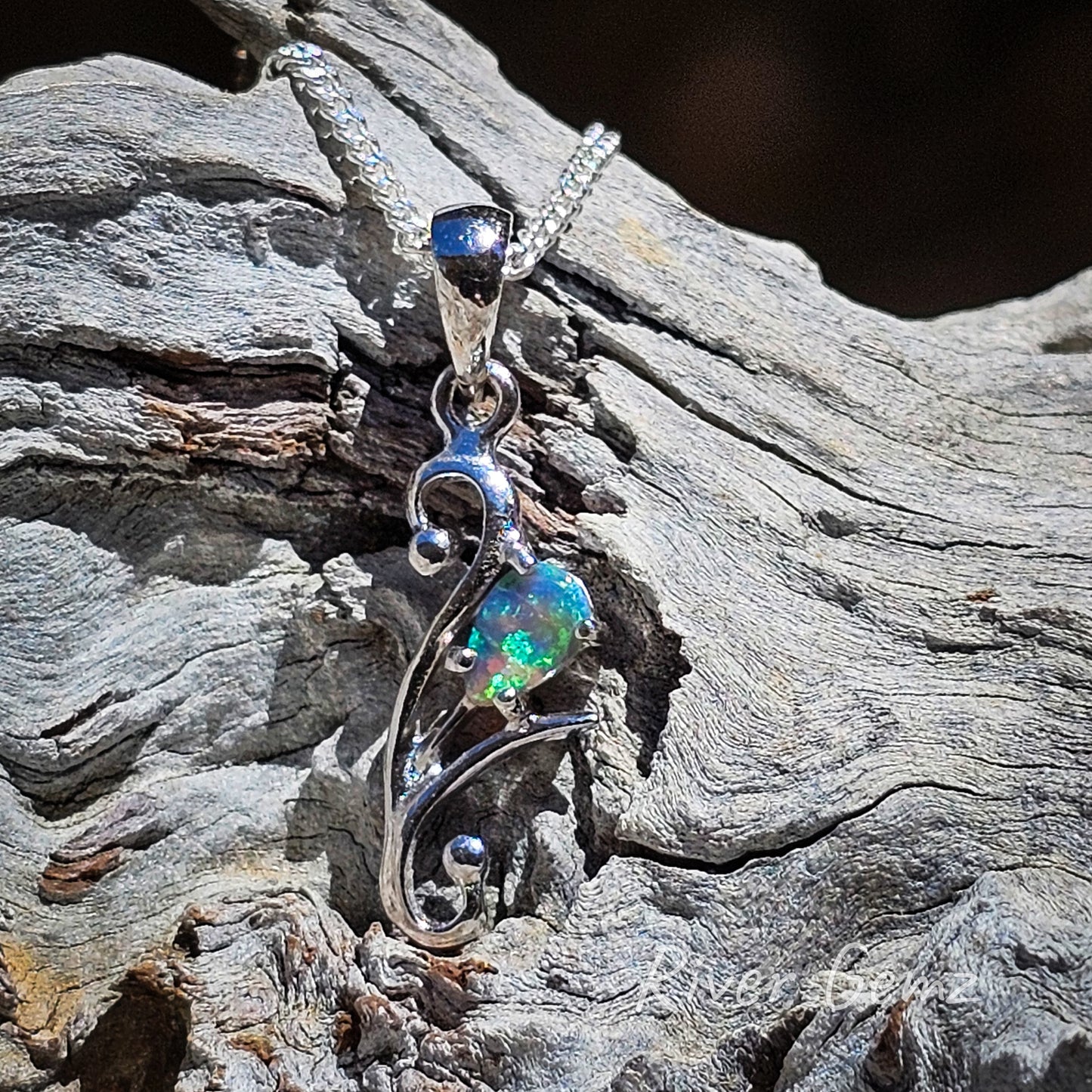 Blue and green coloured black opal in a flower stem setting in the silver necklace.