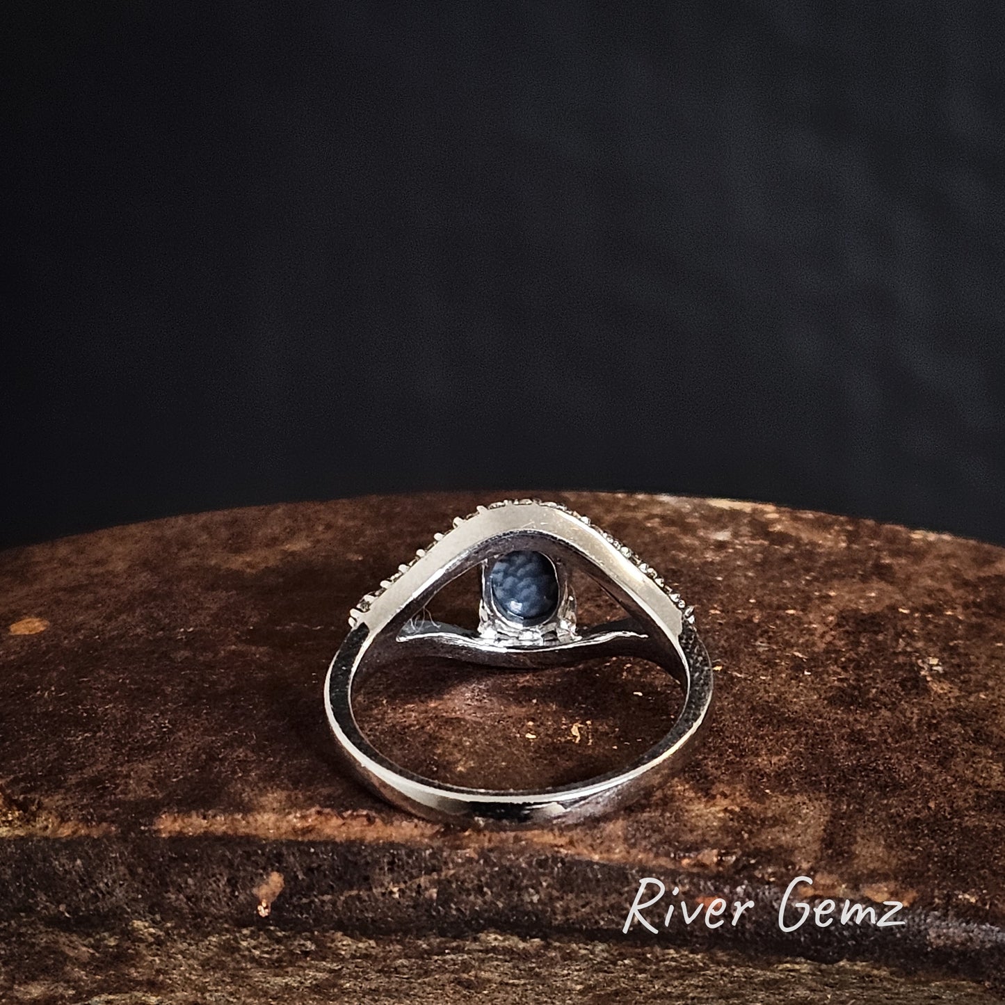 Rear view of silver ring showing the black base of the opal on a iron shoe anvil, branded 'River Gemz'.