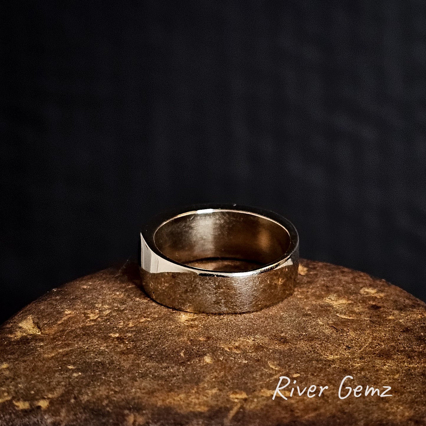 Rear view of white gold ring on a textured surface with 'River Gemz' branding.