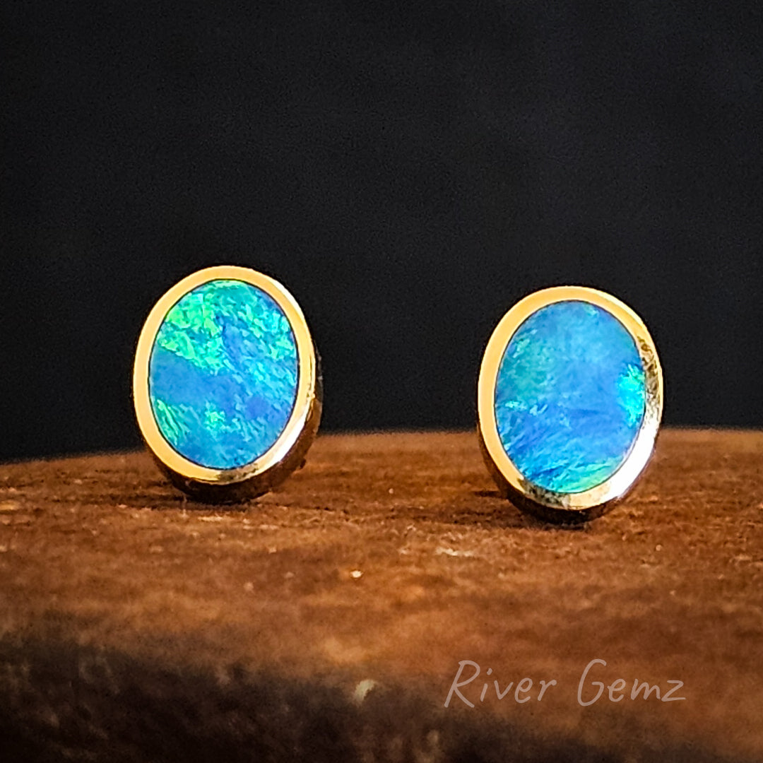 Blue and green swirls of colour in the dark oval shaped opals in gold earrings.