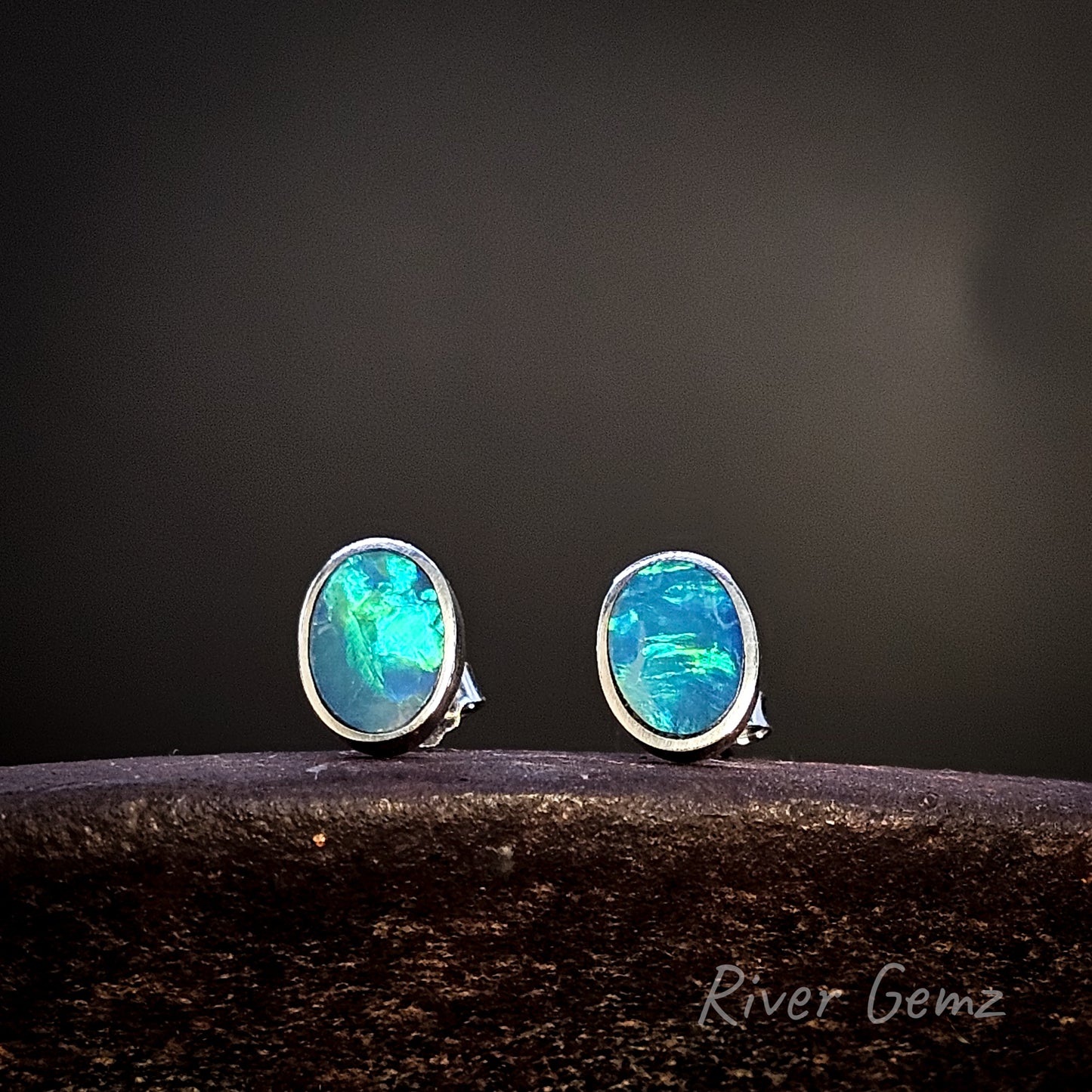 Oval shaped opal stud earrings on a dark background with 'River Gemz' branding.