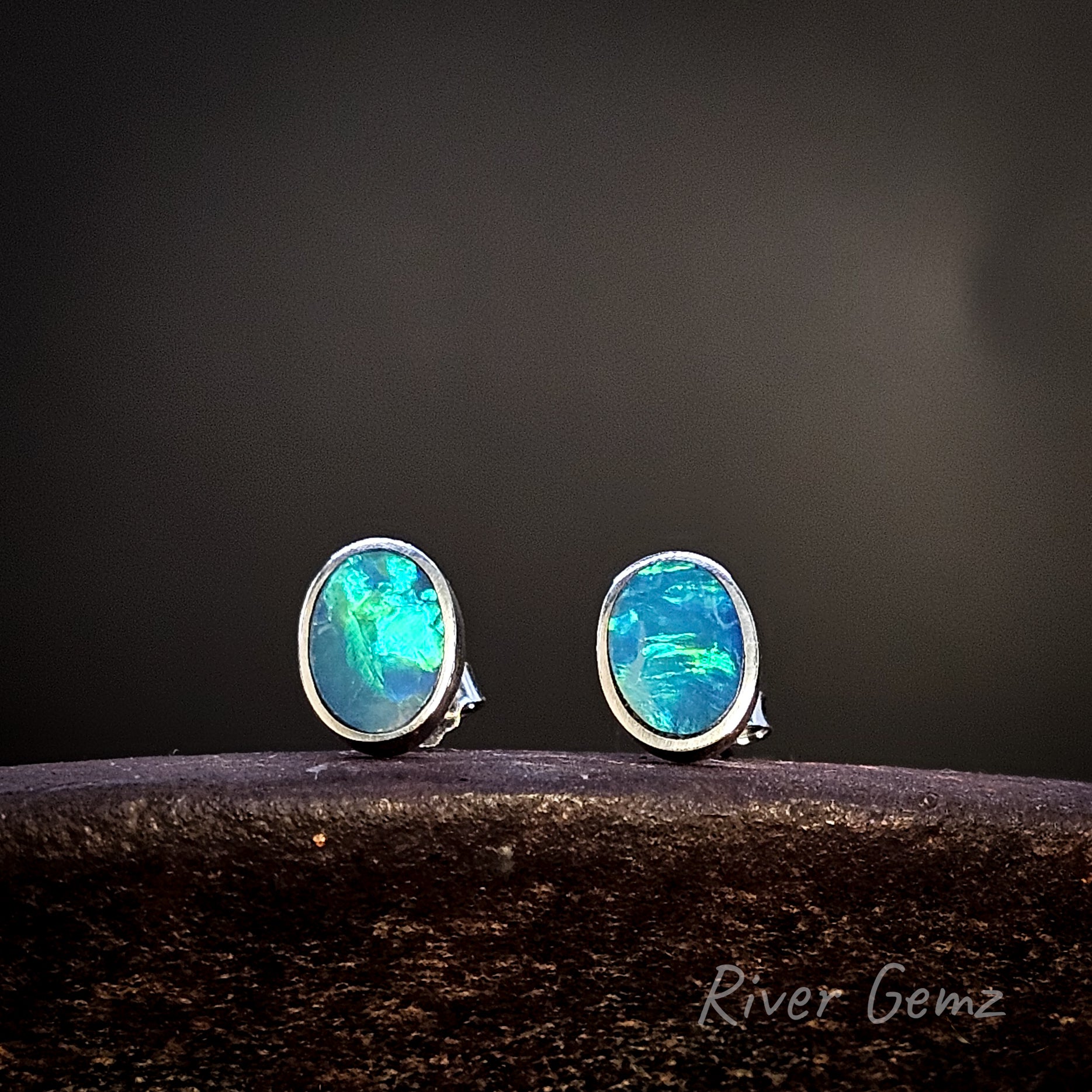 Oval shaped opal stud earrings on a dark background with 'River Gemz' branding.
