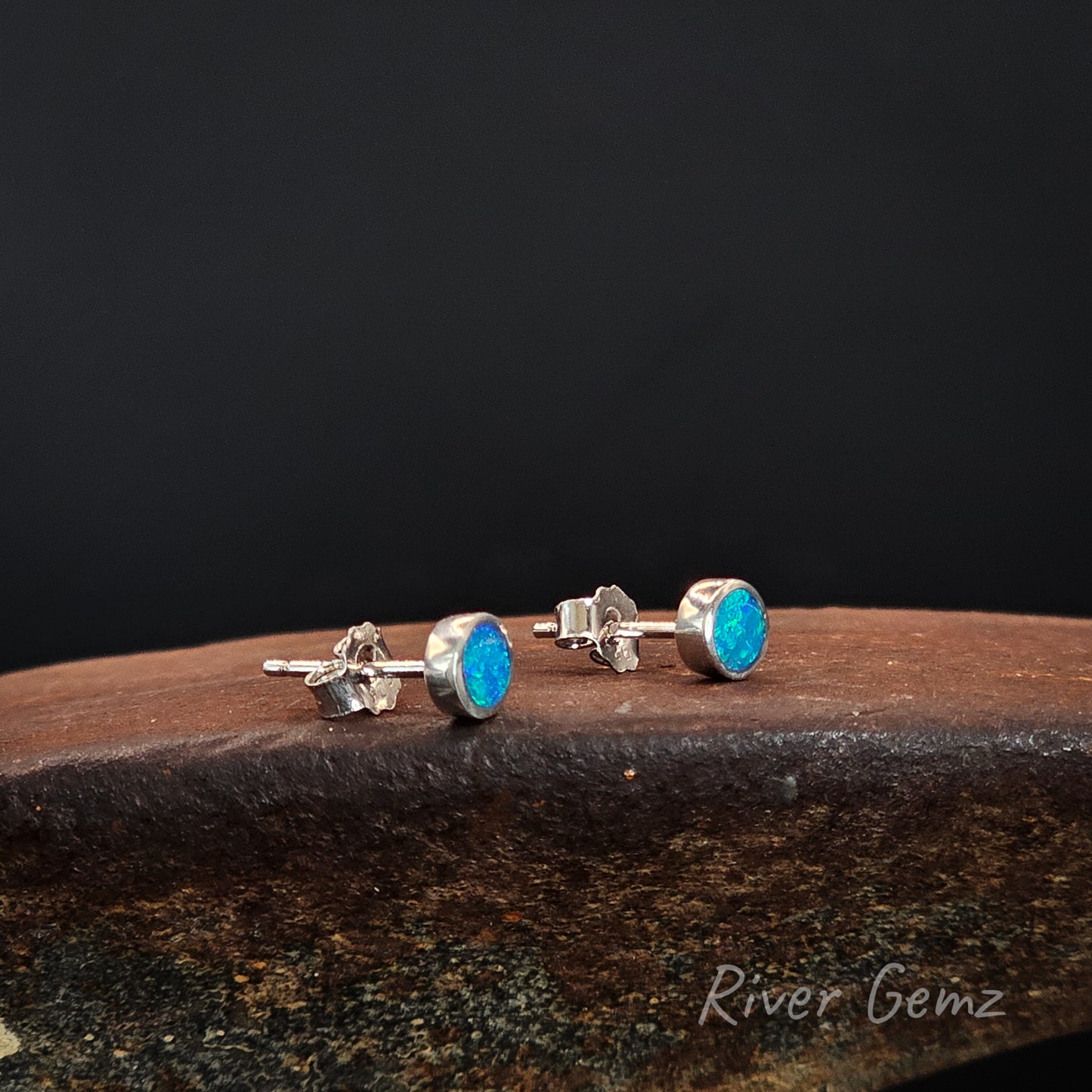 Pair of round faced stud earrings with blue and green opals.