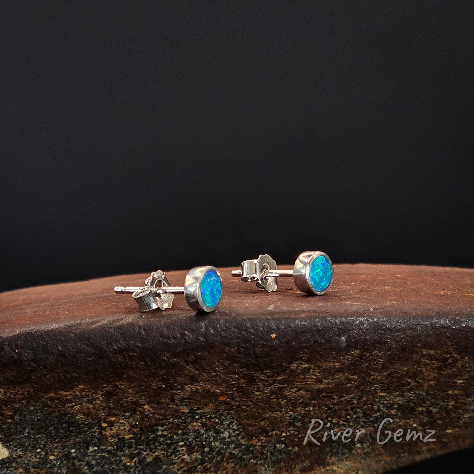 Pair of round faced stud earrings with blue and green opals.