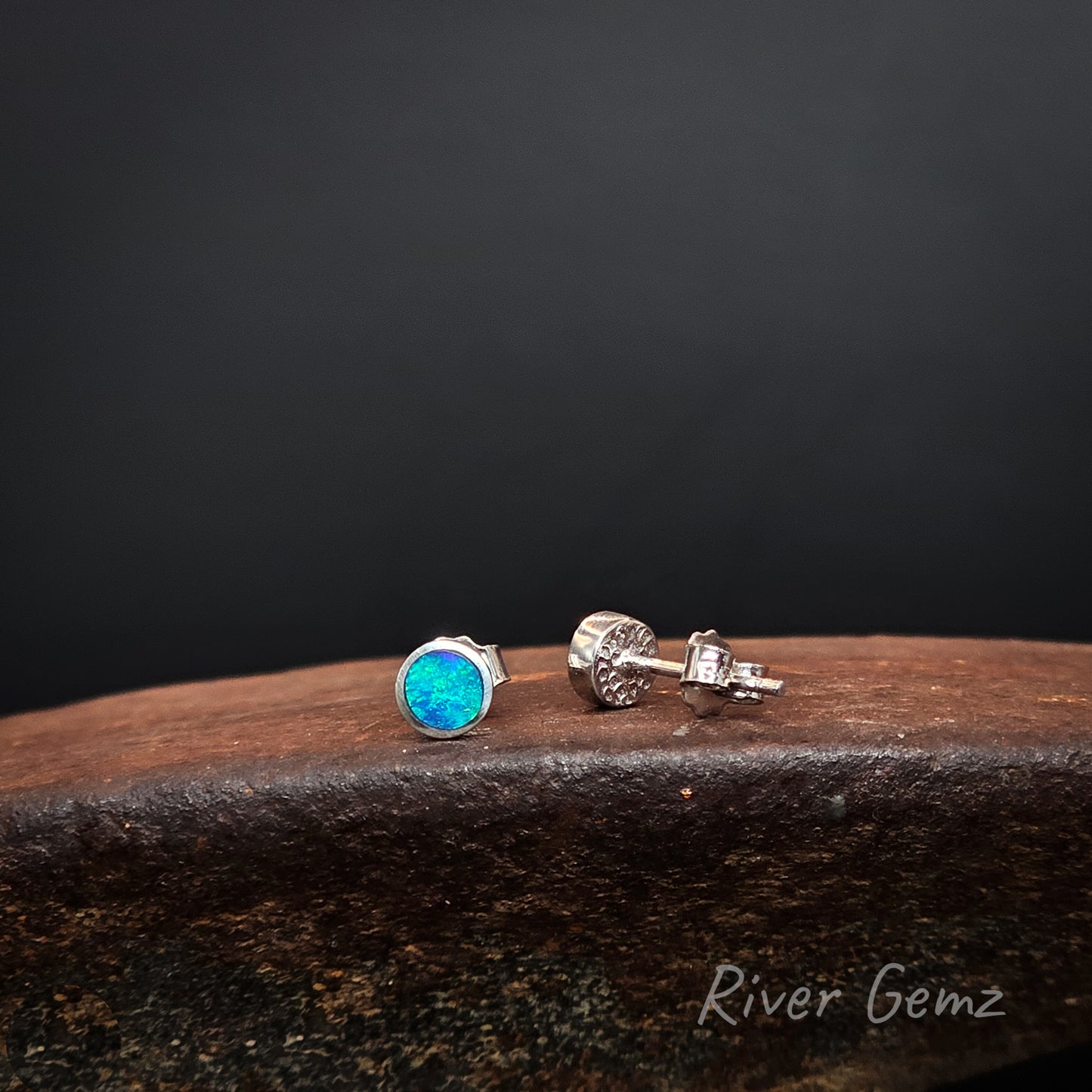 Blue and green dark opals besel set in sterling silver stud earrings with silver backing shown on the right earring.