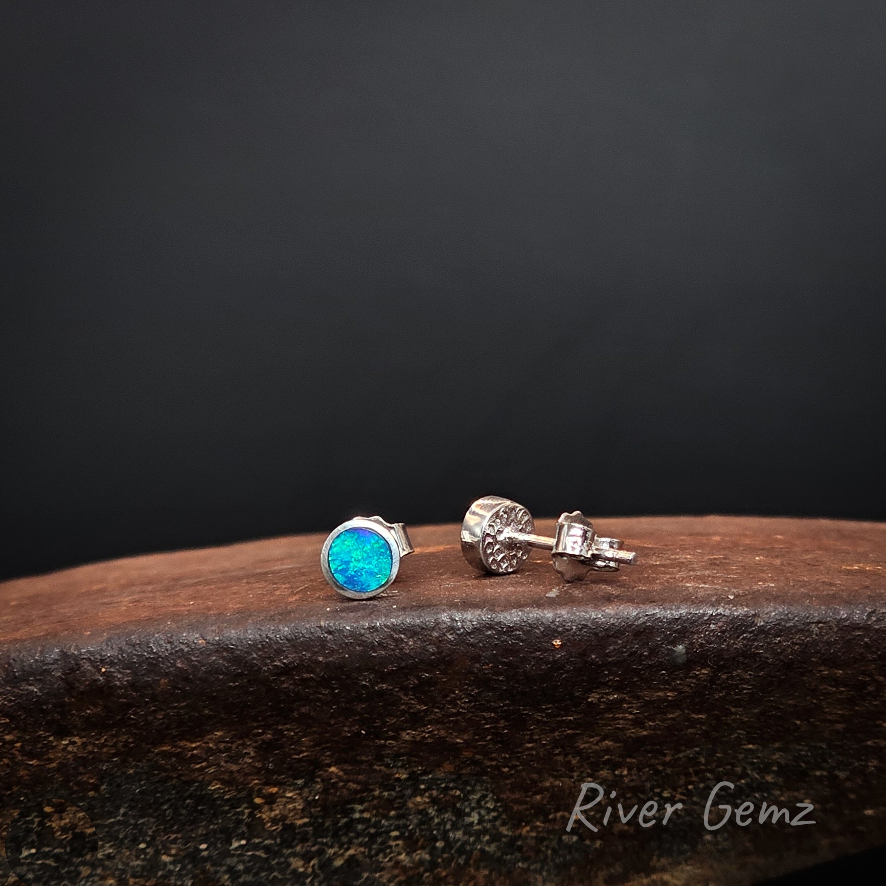 Blue and green dark opals besel set in sterling silver stud earrings with silver backing shown on the right earring.