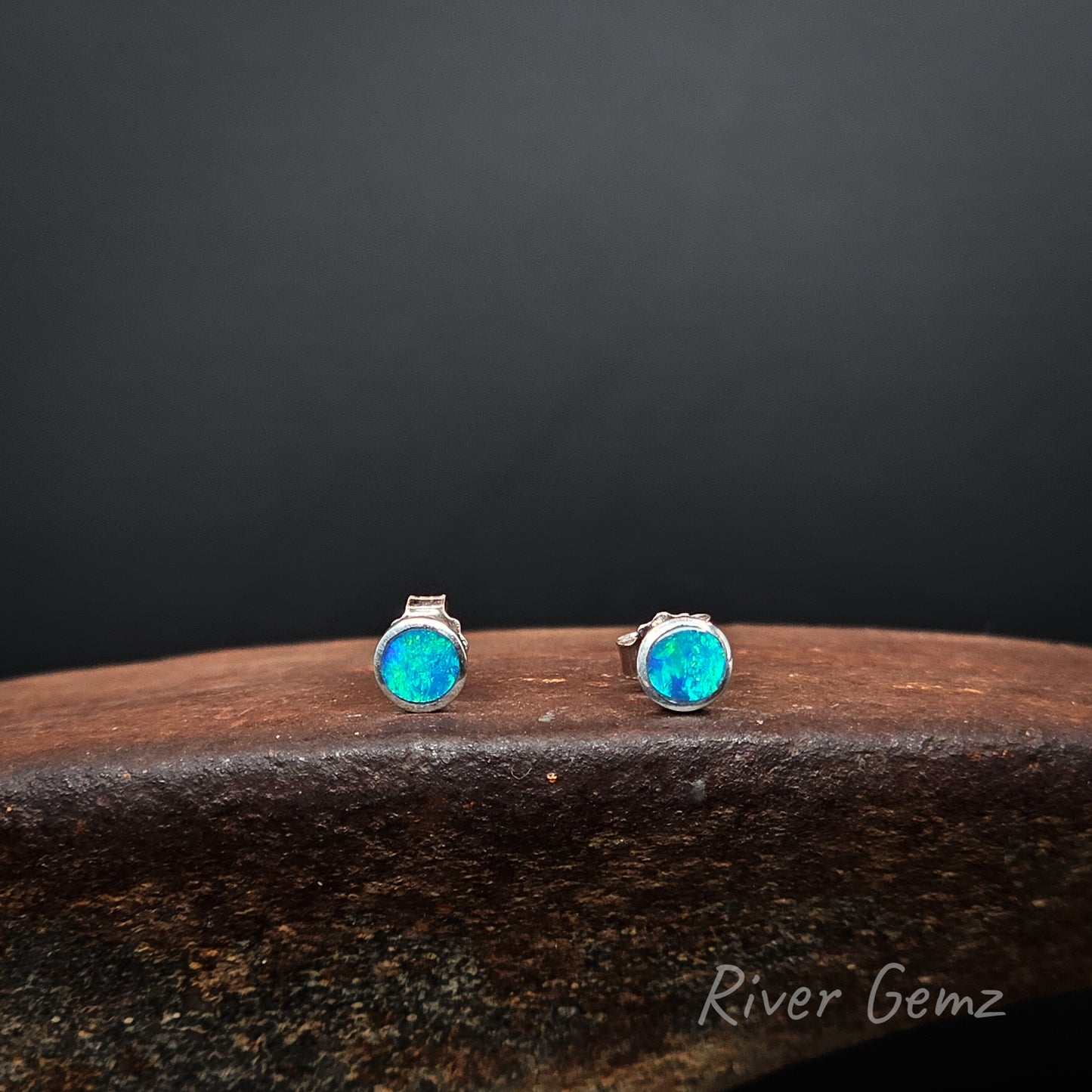 Bright green and blue opals set in silver stud earrings.