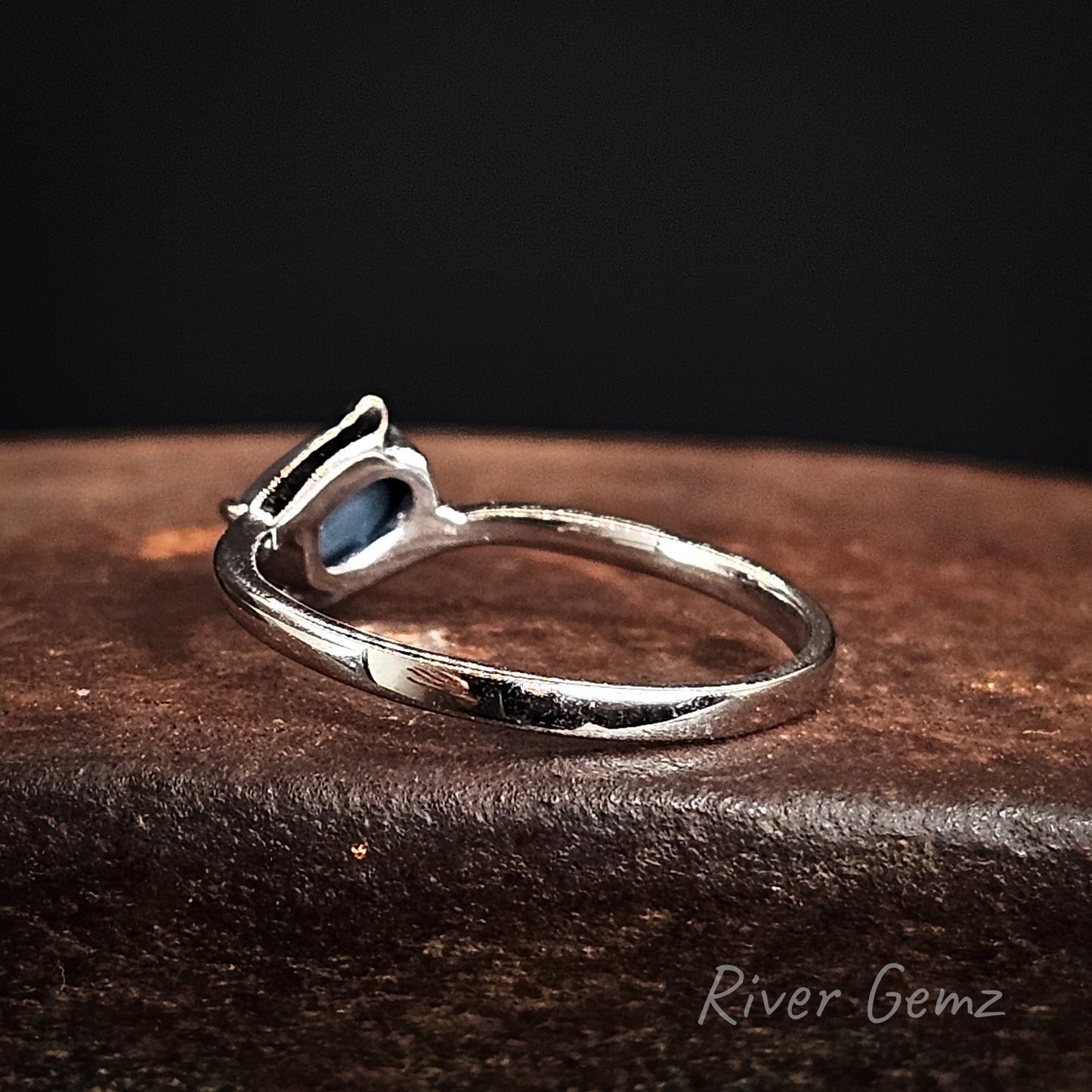 Rear view shows the dark base tone of the included black opal in the high grade white opal ring on a dark surface, featuring 'River Gemz' branding.