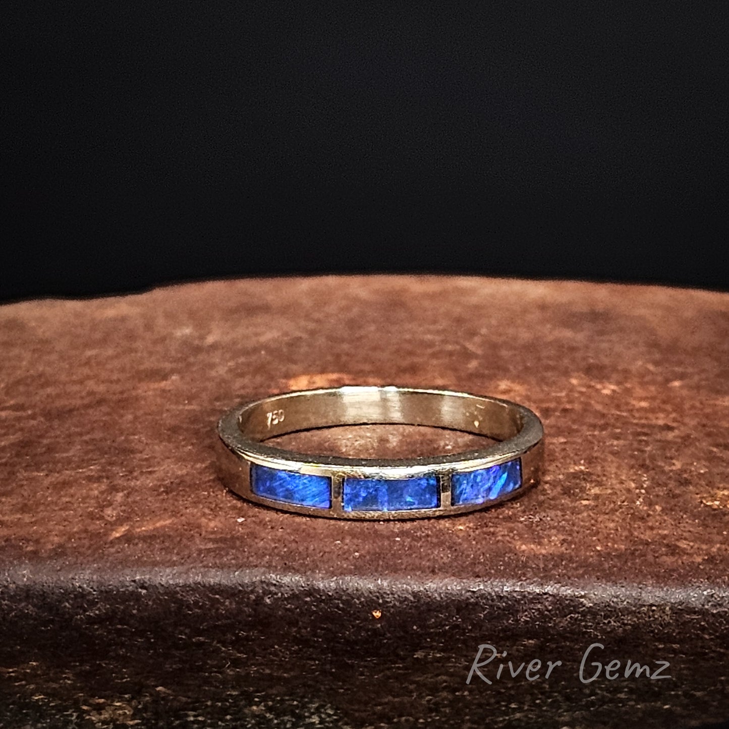 18K white gold ring with 3 blue coloured black opals on a dark surface, branded 'River Gemz'.