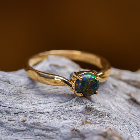 Magnificent array of colours embody the black opal claw set in the narrow shank yellow gold ring.