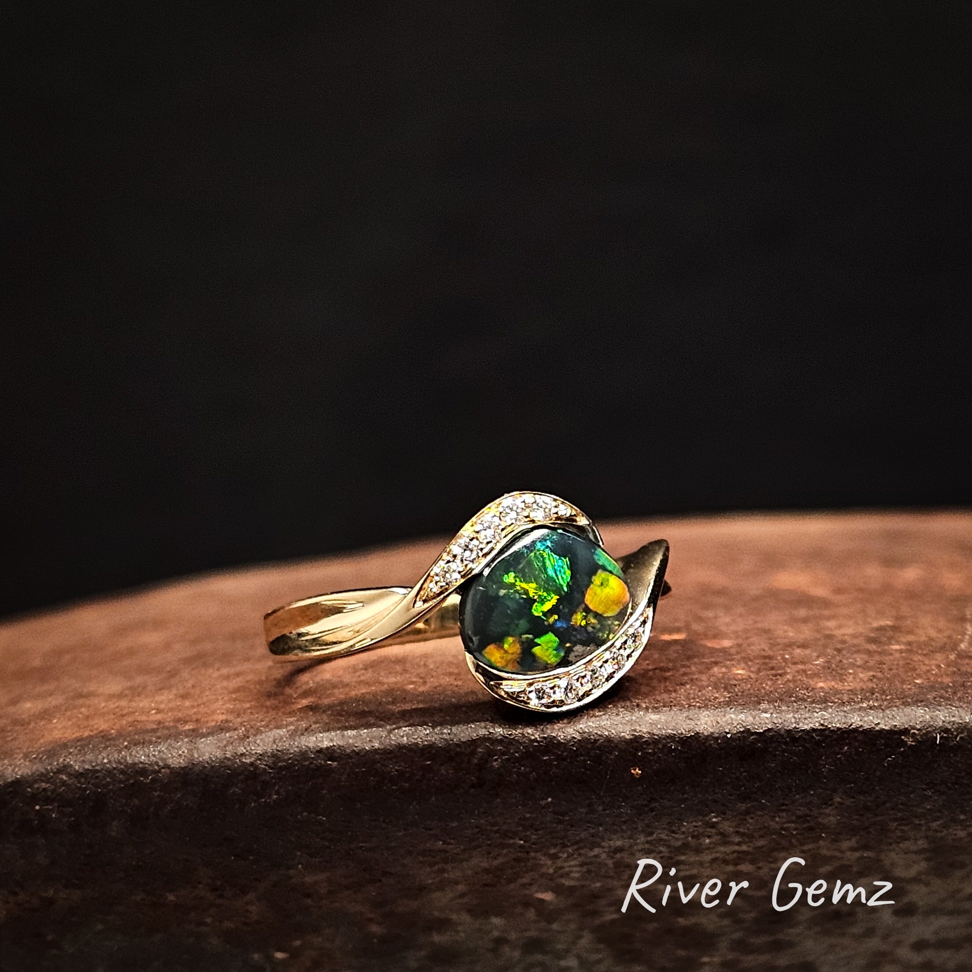 Yellow, green and blue dark opal with channel set diamonds in a high grade gold ring.