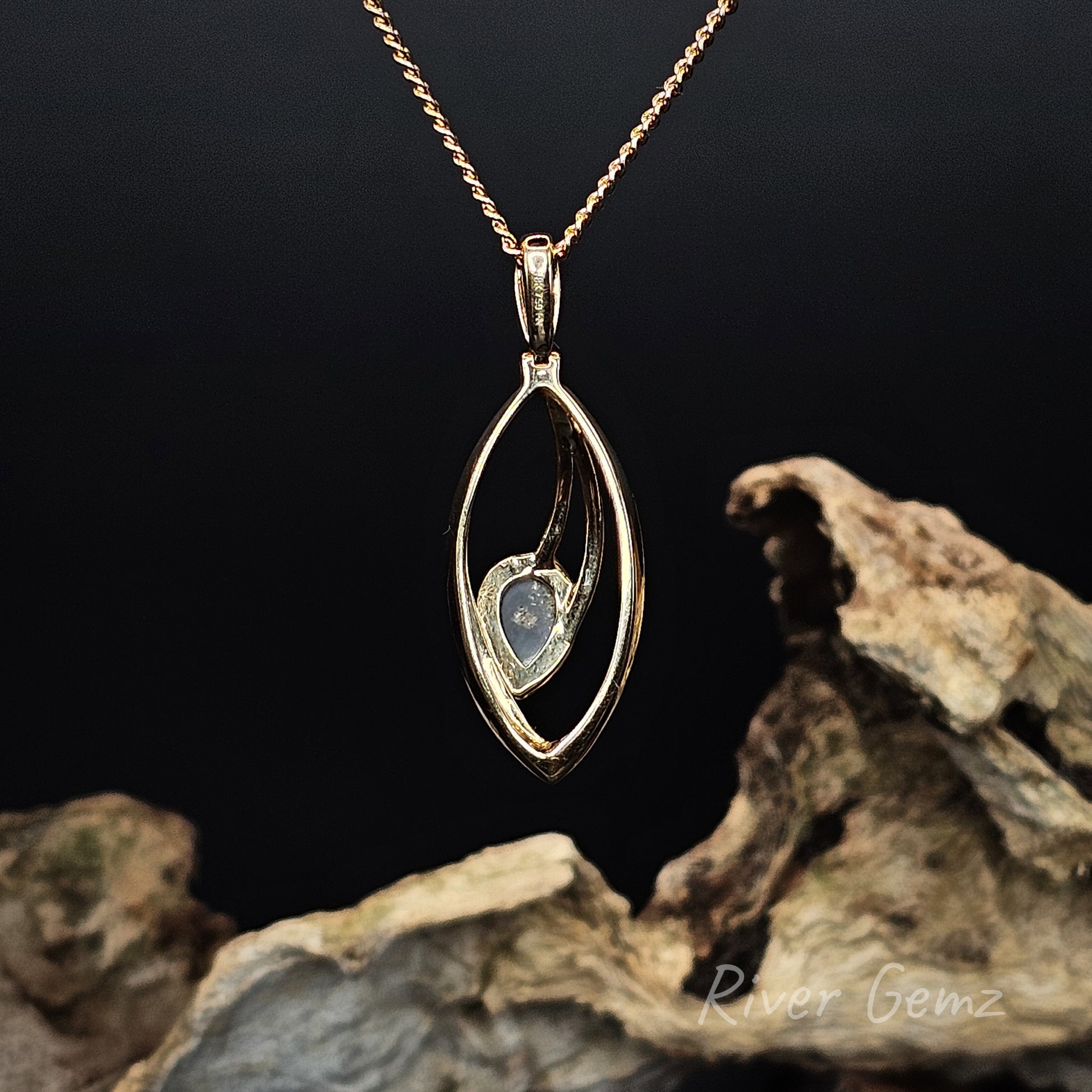 Rear view of the necklace shows the dark base tone of the black opal set in it on a dark background