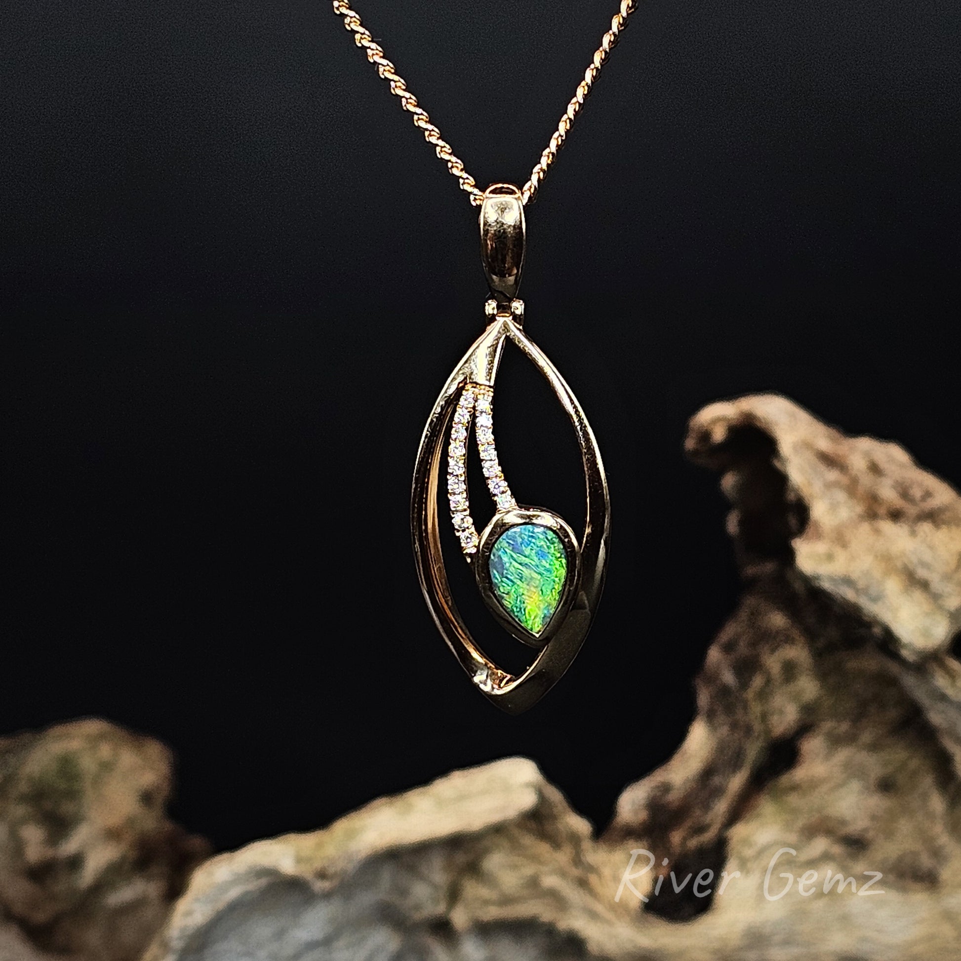Gold pendant with a green black opal and multiple channel set diamonds on a dark background