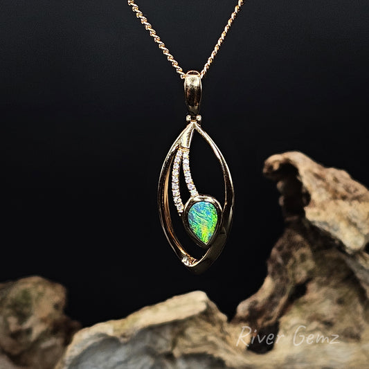 Gold pendant with a green black opal and multiple channel set diamonds on a dark background