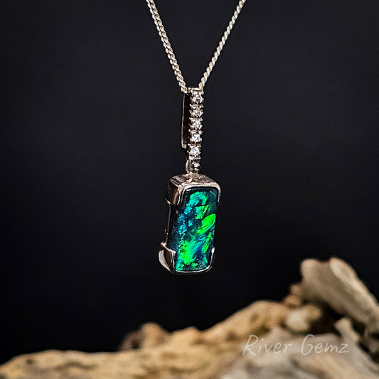 Opal and white diamonds in white gold necklace with silver chain on a dark background.