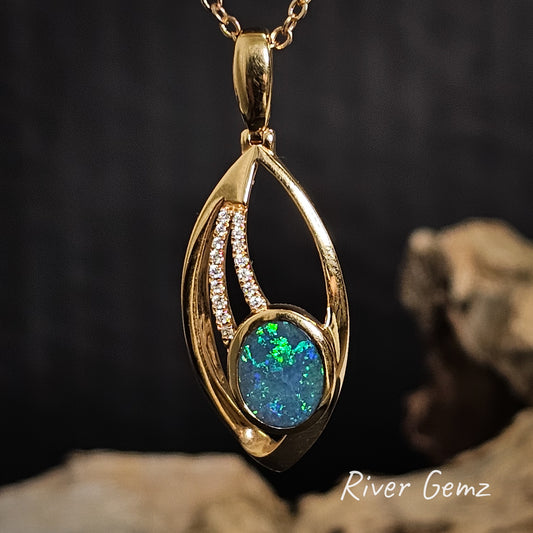 Gold pendant with opal stone and diamonds on a dark background, branded 'River Gemz'.