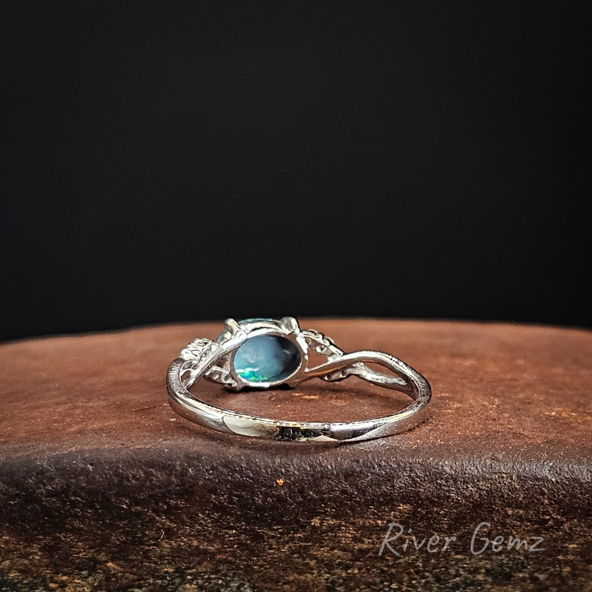 Rear view of white gold ring showing the dark tone of the included black opal on a dark background.