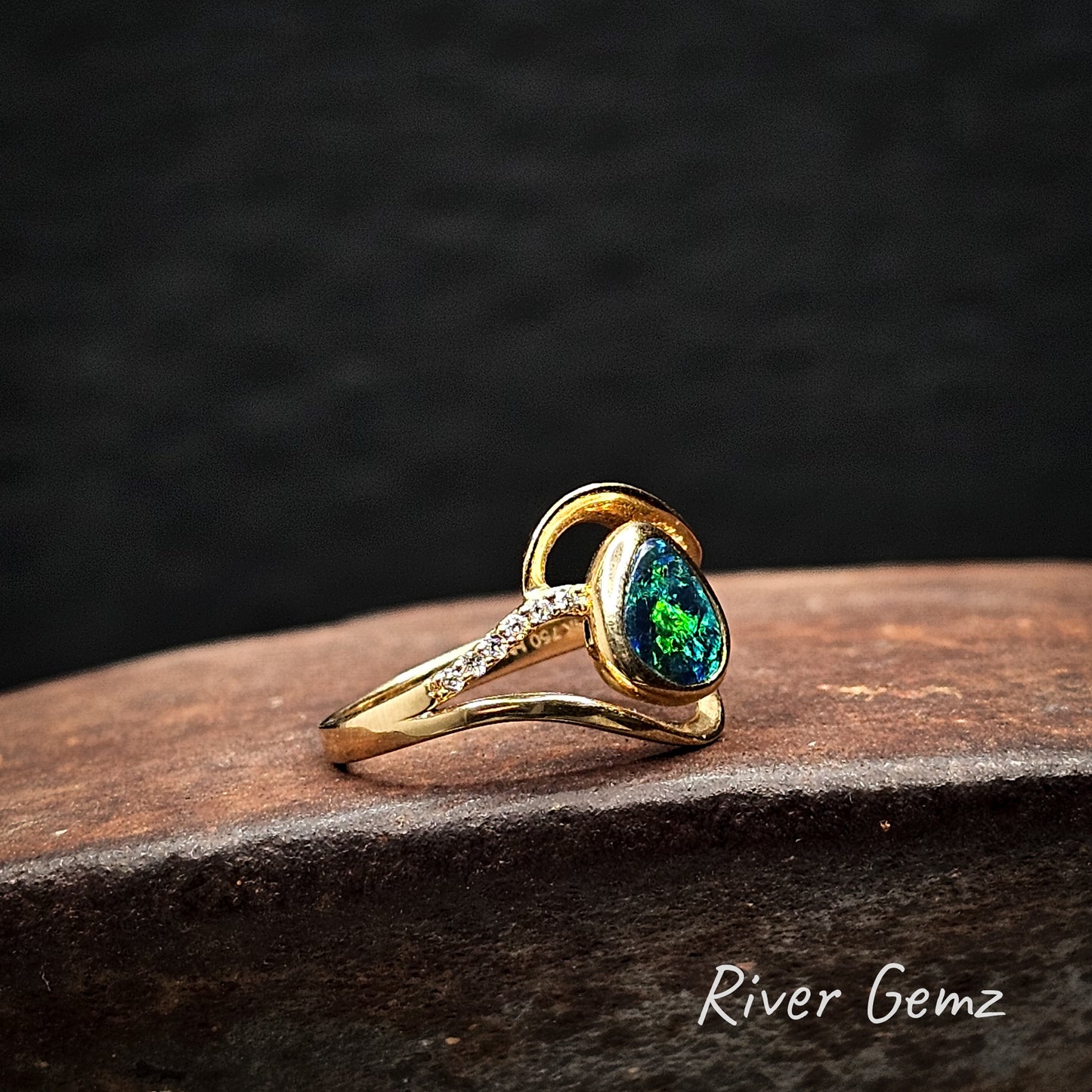 Tear drop shaped black opal set in gold ring with a row of diamonds on the shoulders.