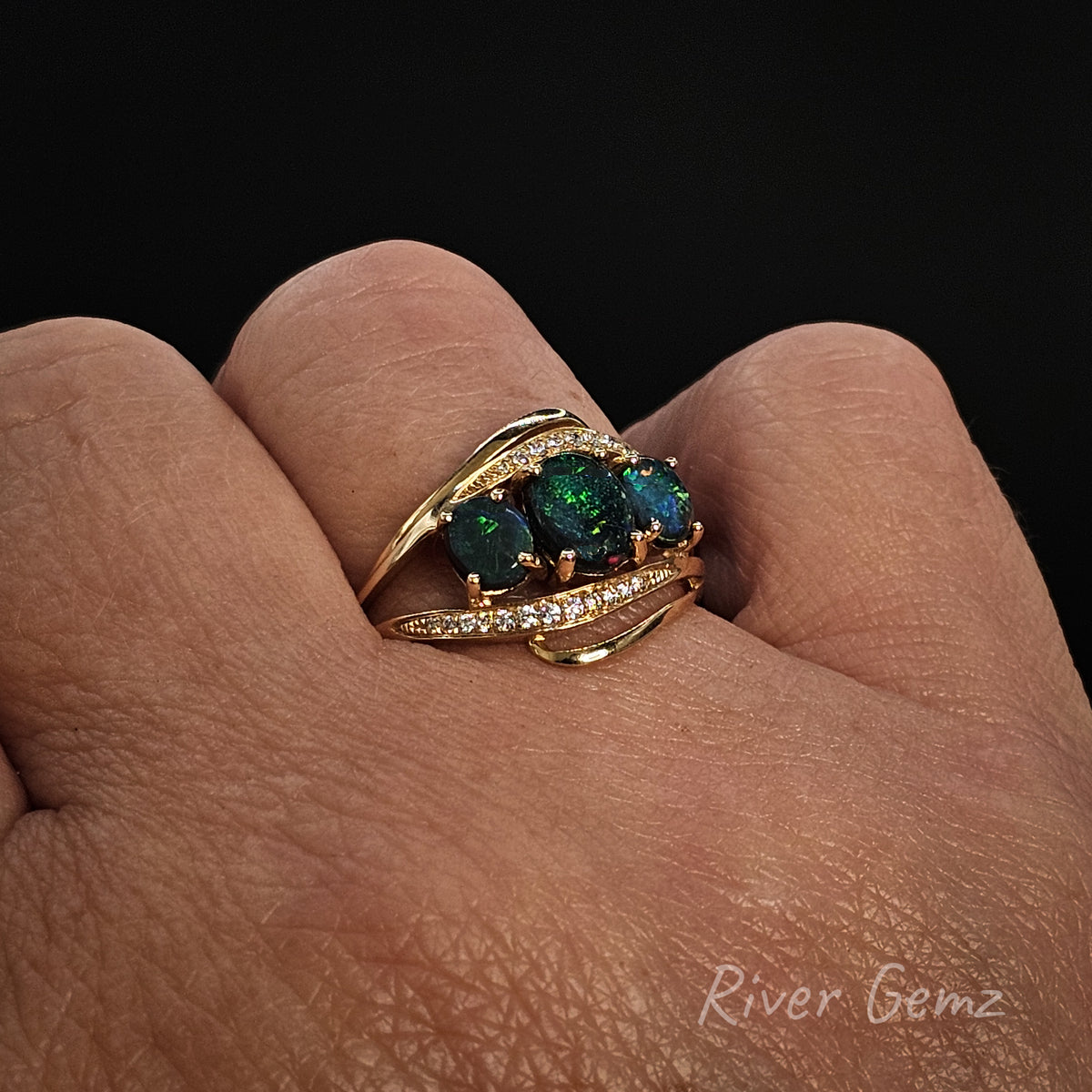 Trilogy opal and diamond ring worn on right hand ring finger against a black background with 'River Gemz' watermark in the bottom right hand corner.