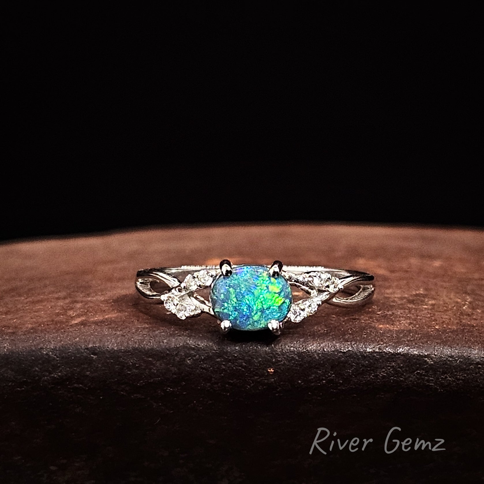 Oval shaped green dark opal and diamonds on the shoulders of the white gold ring.