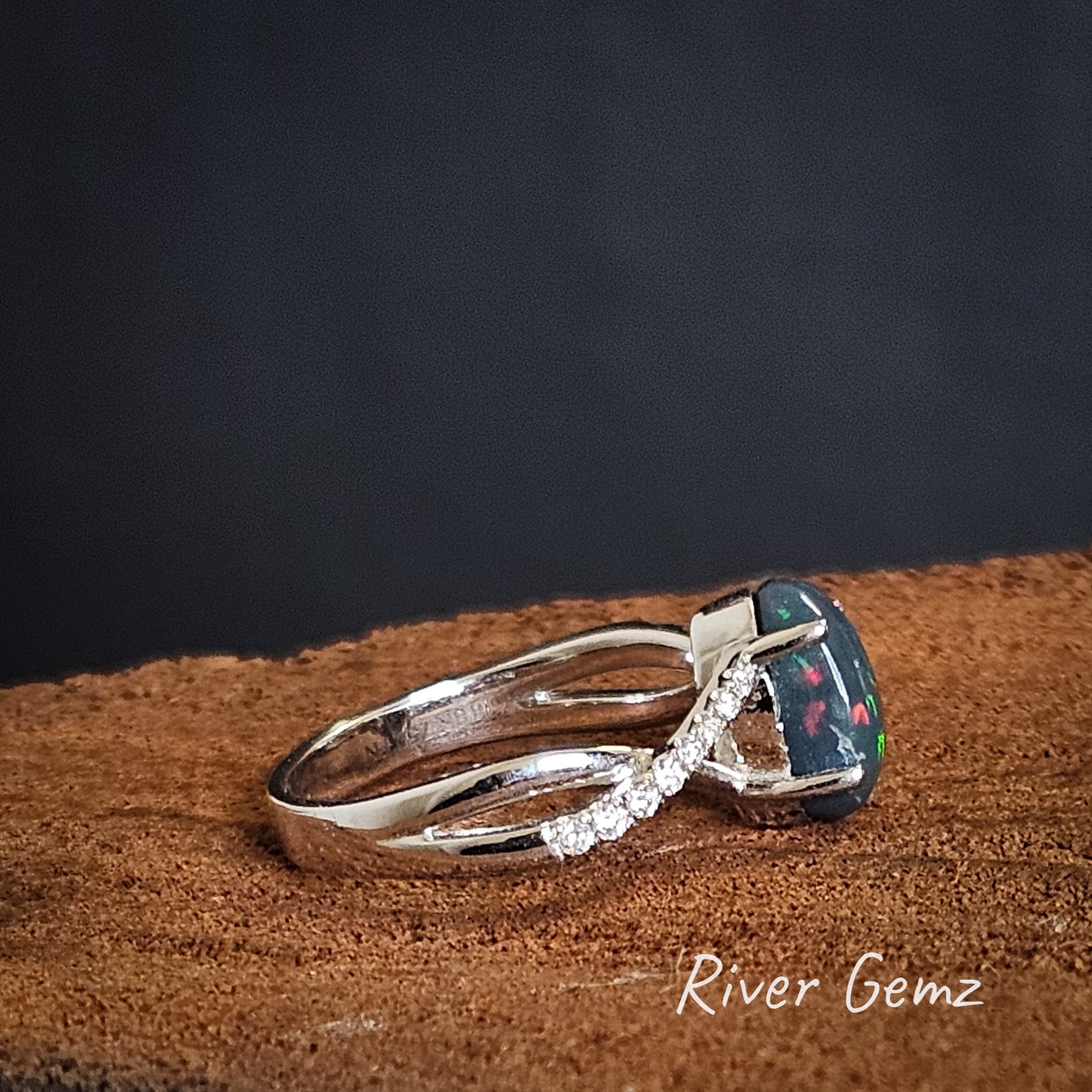 Side view shows the high domed cut of the black opal and the colours extending to the sides of the stone.