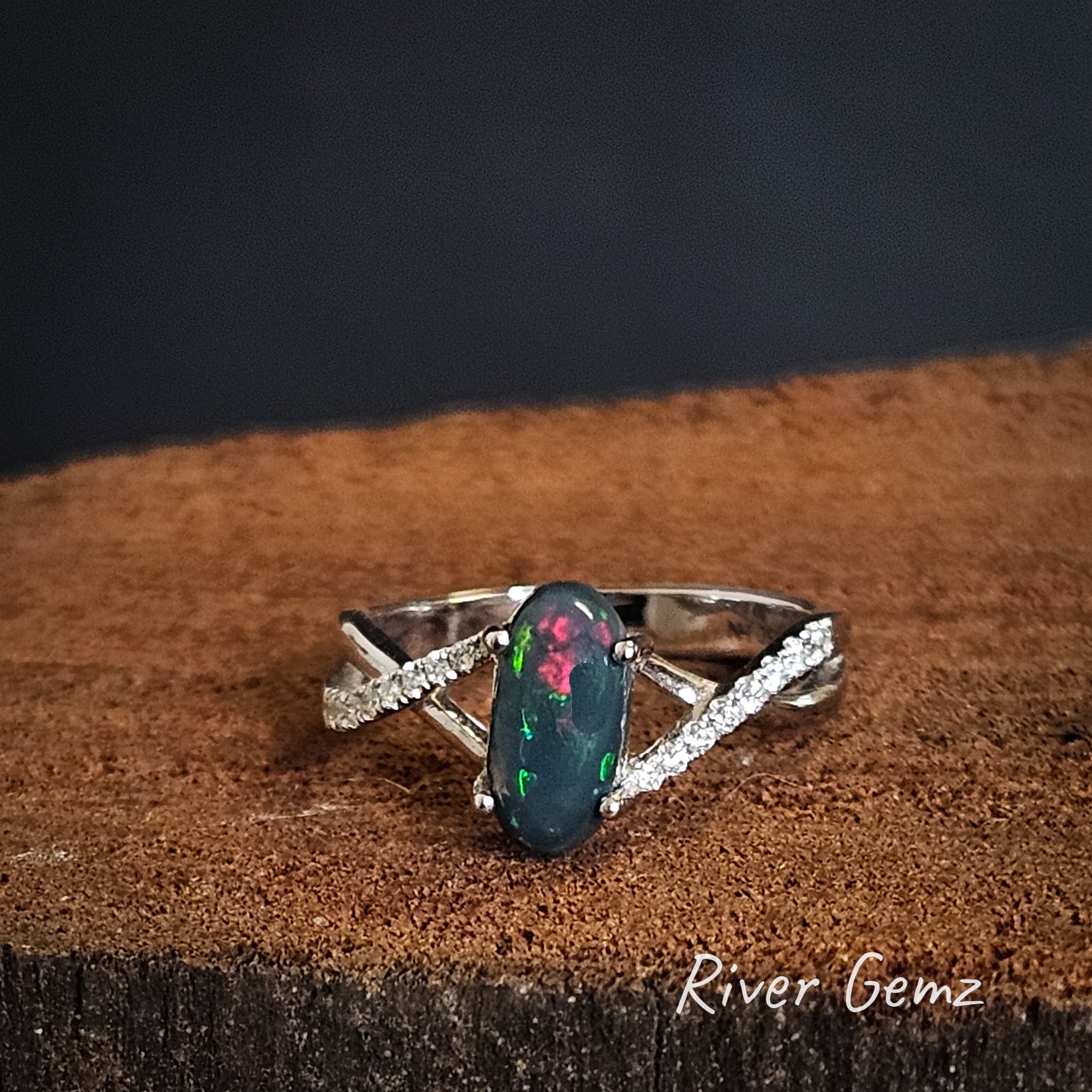 Oval shaped black opal claw set in high grade white gold ring with channel set diamonds on the shoulders.