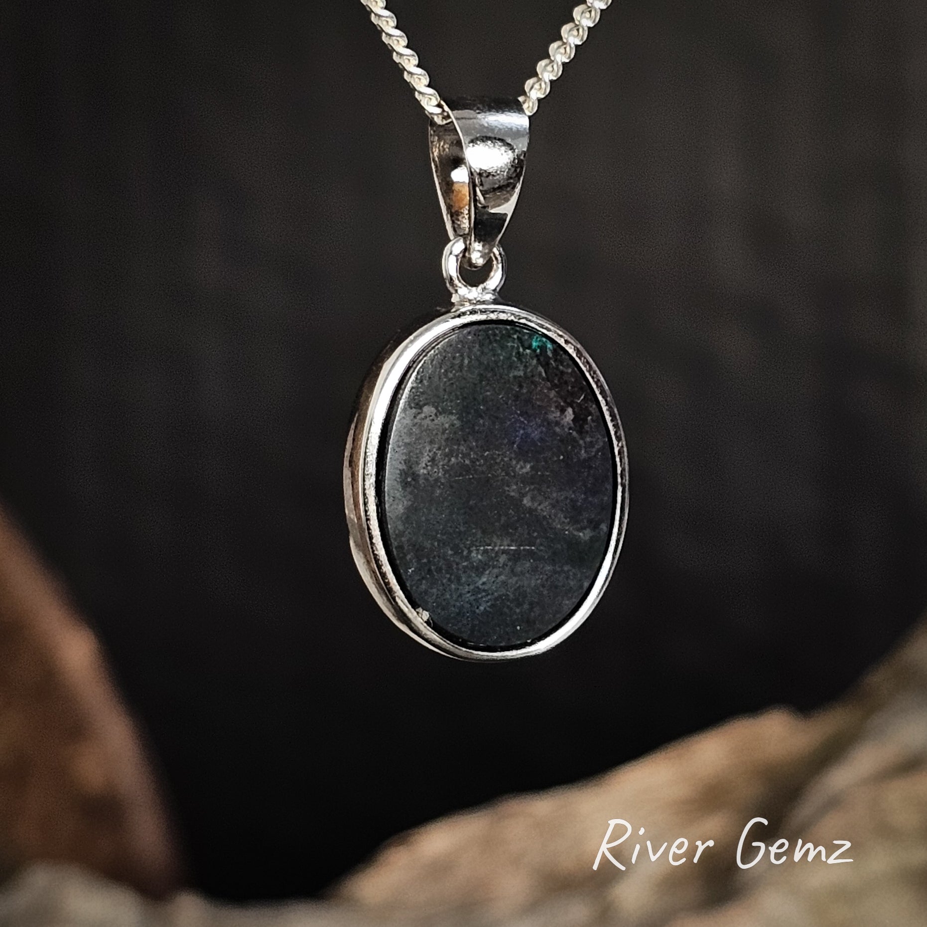 Back of the silver pendant showing the dark base of the inserted black opal on a dark background, featuring 'River Gemz' branding.