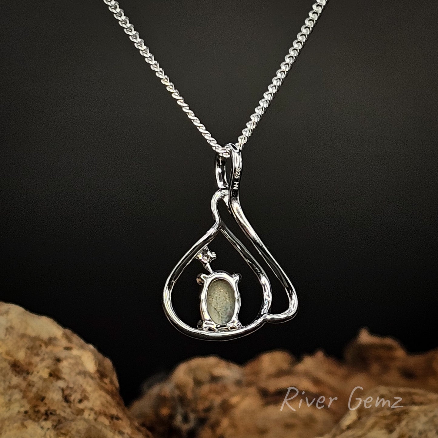 Silver pendant with a green stone on a dark background
