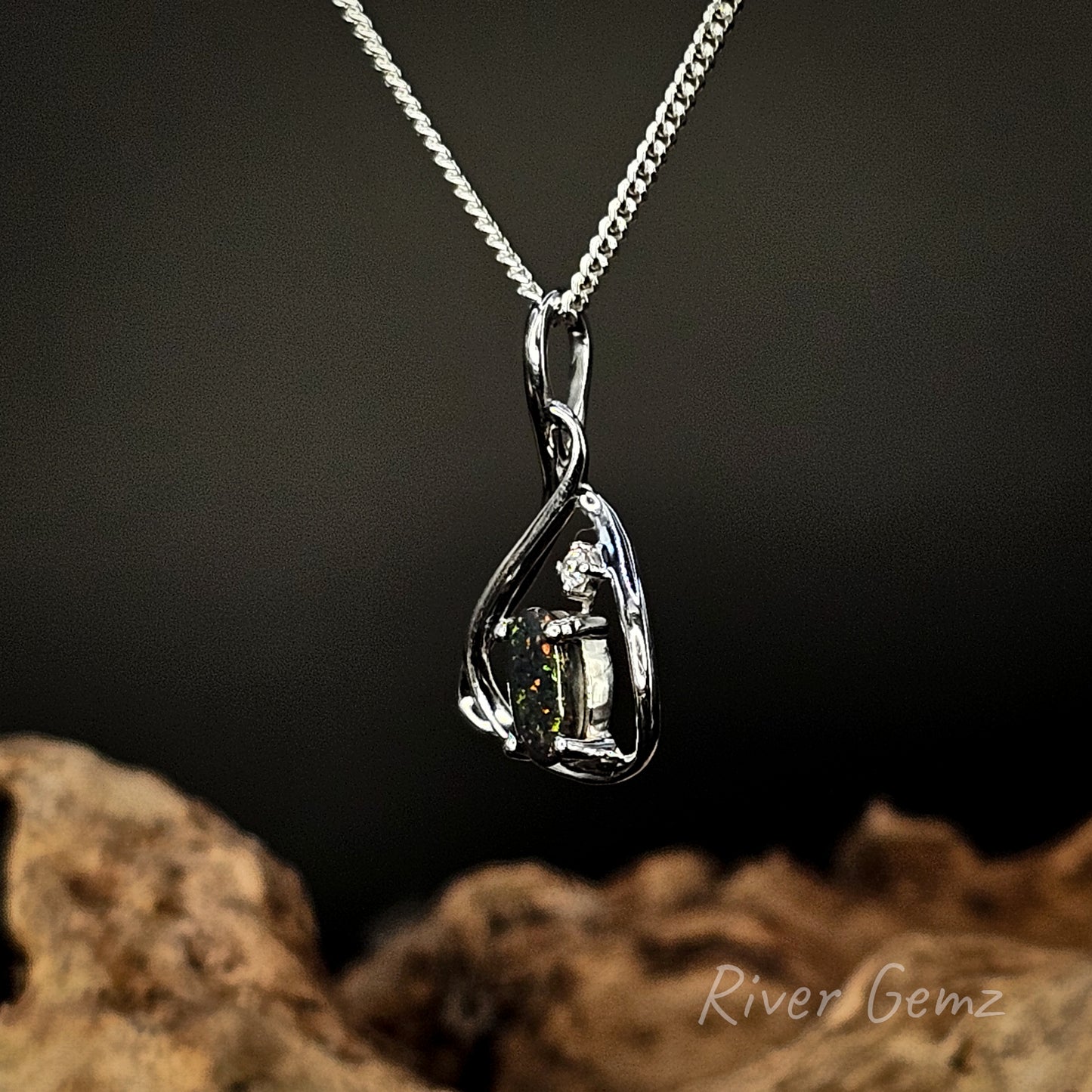 Silver pendant necklace with a dark stone on a dark background