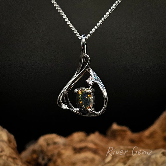 Silver pendant with a gemstone on a dark background, featuring 'River Gemz' branding.