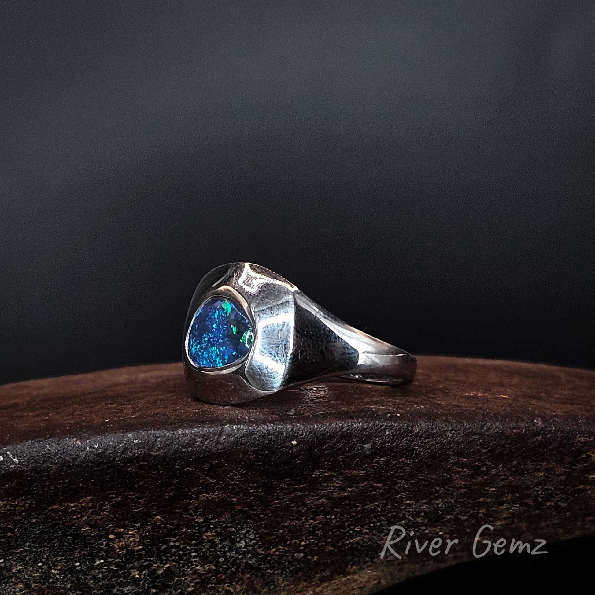 Side view of the ring shows the lines of the sterling silver ring with vivid blue coloured black opal.