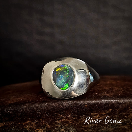 Silver ring with a colorful black opal on a dark background, featuring the brand 'River Gemz'.