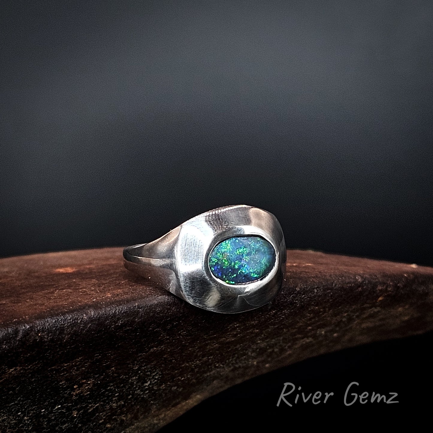 Blue and green black opal besel set in men's silver ring with tapered shoulders.