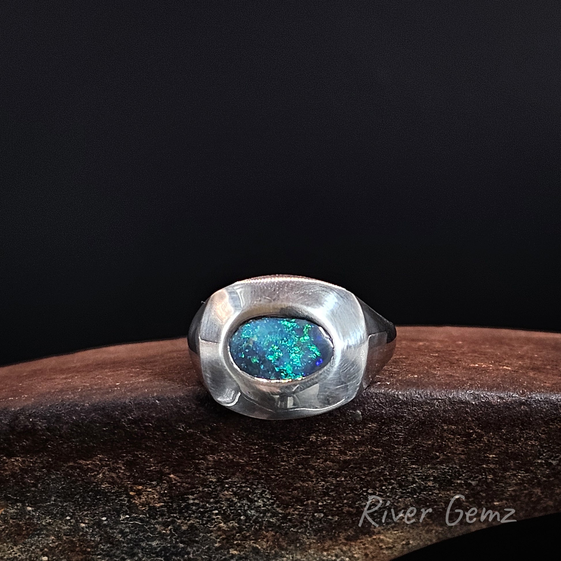 Bright green and dark blue oval shaped opal besel set in sterling silver ring.