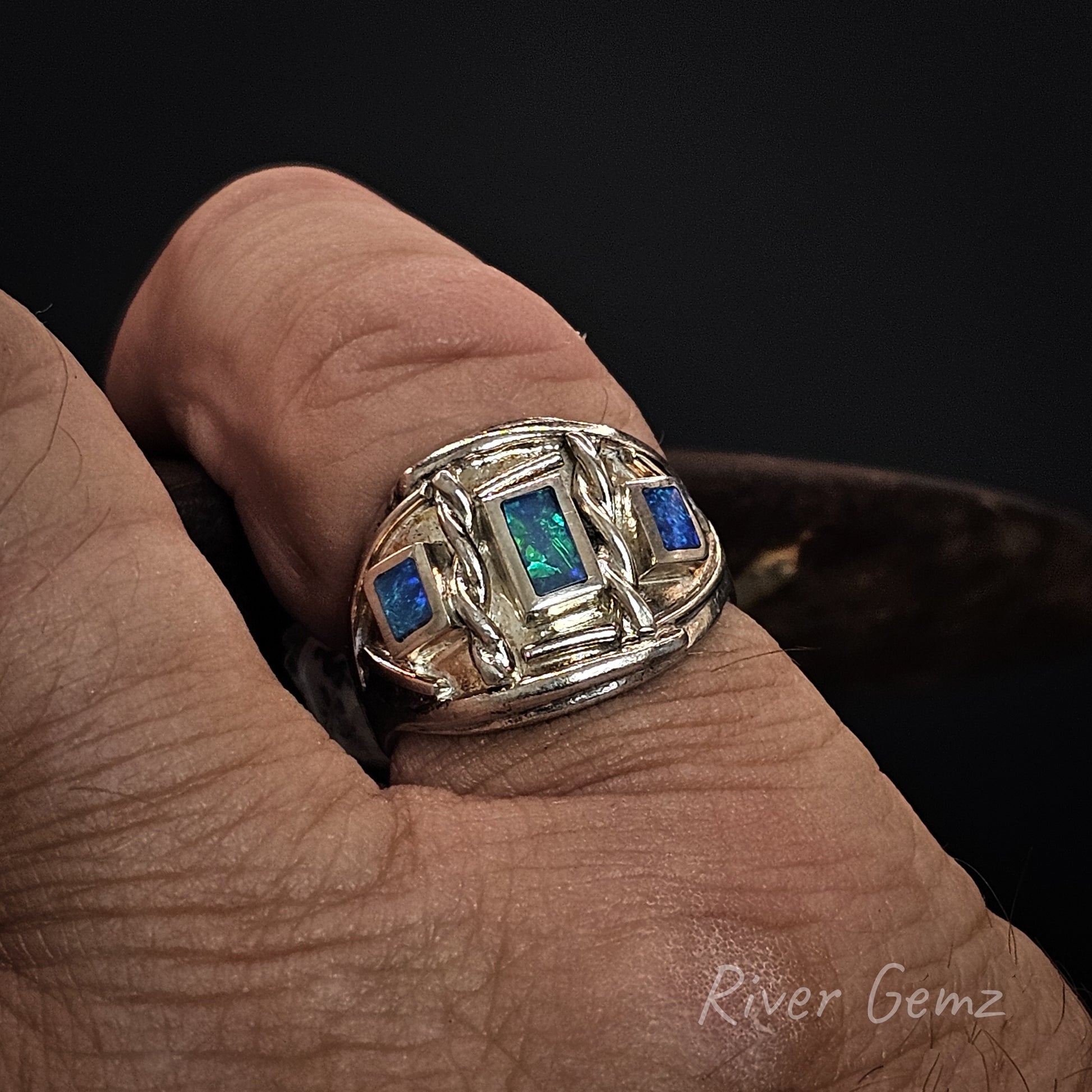 3 rectangular shaped blue-green opals set in sterling silver ring worn on finger.