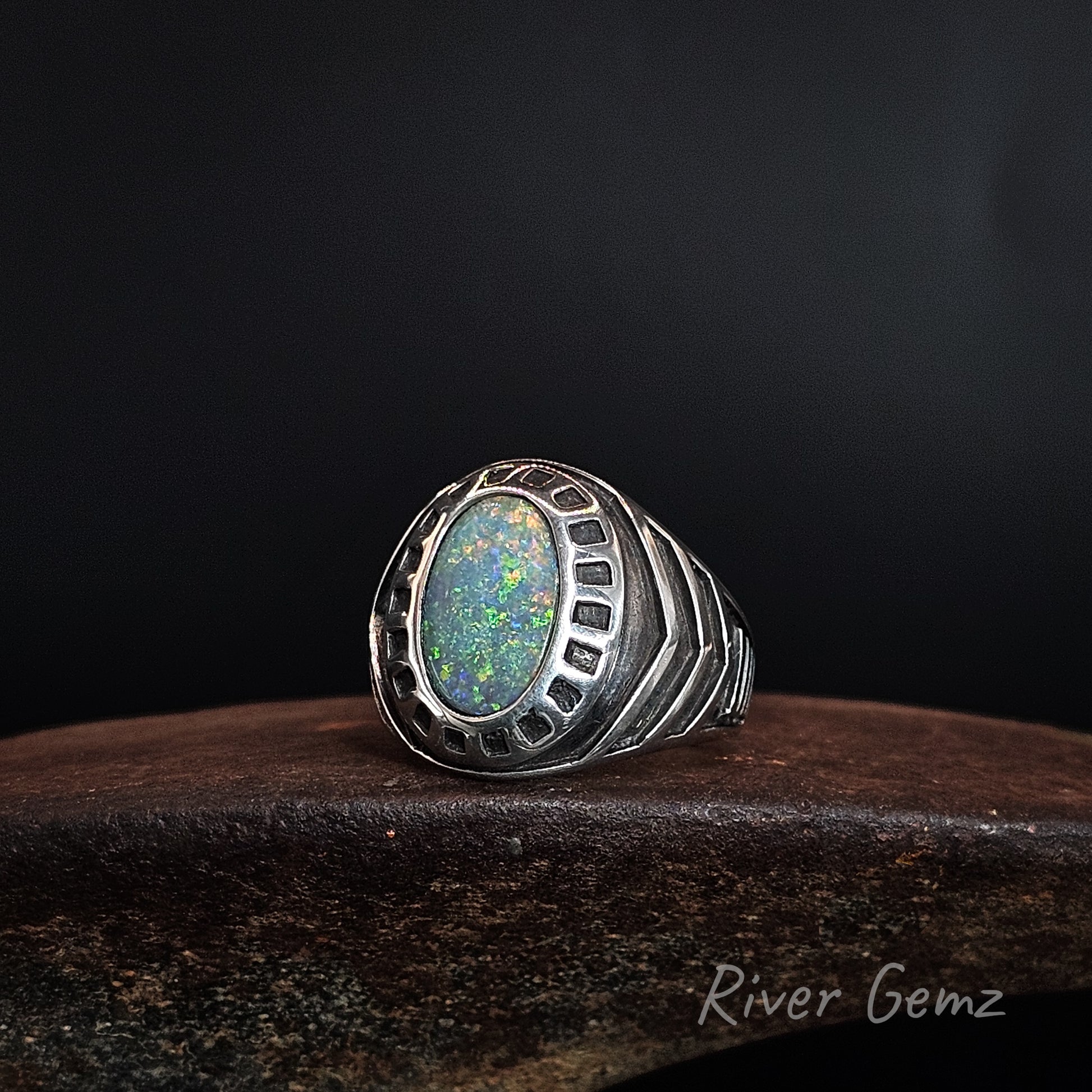 Silver ring with numerous design features, large tapered shoulders and with a colourful black opal.