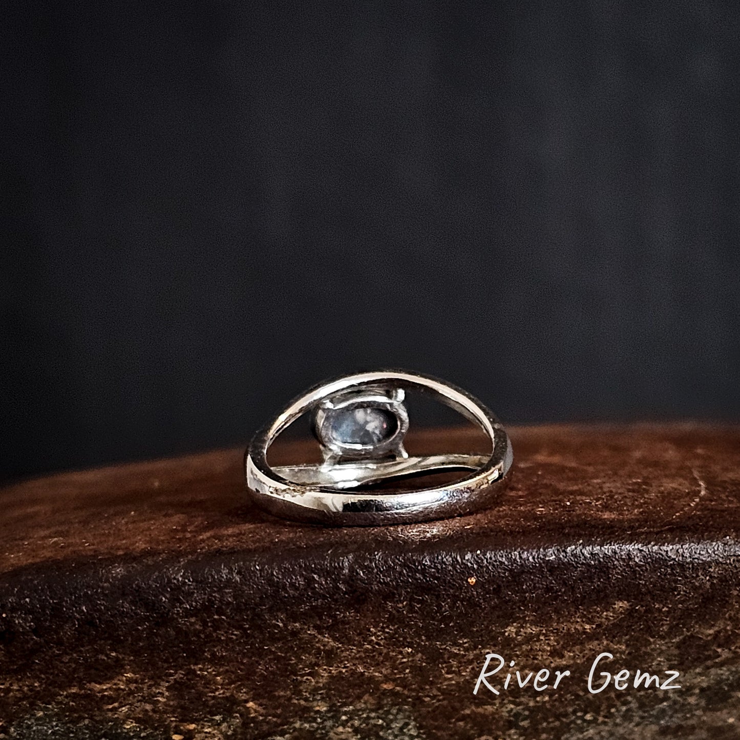 Rear view of the silver ring showing the dark base tone of the black opal on a dark background, featuring the brand 'River Gemz'.