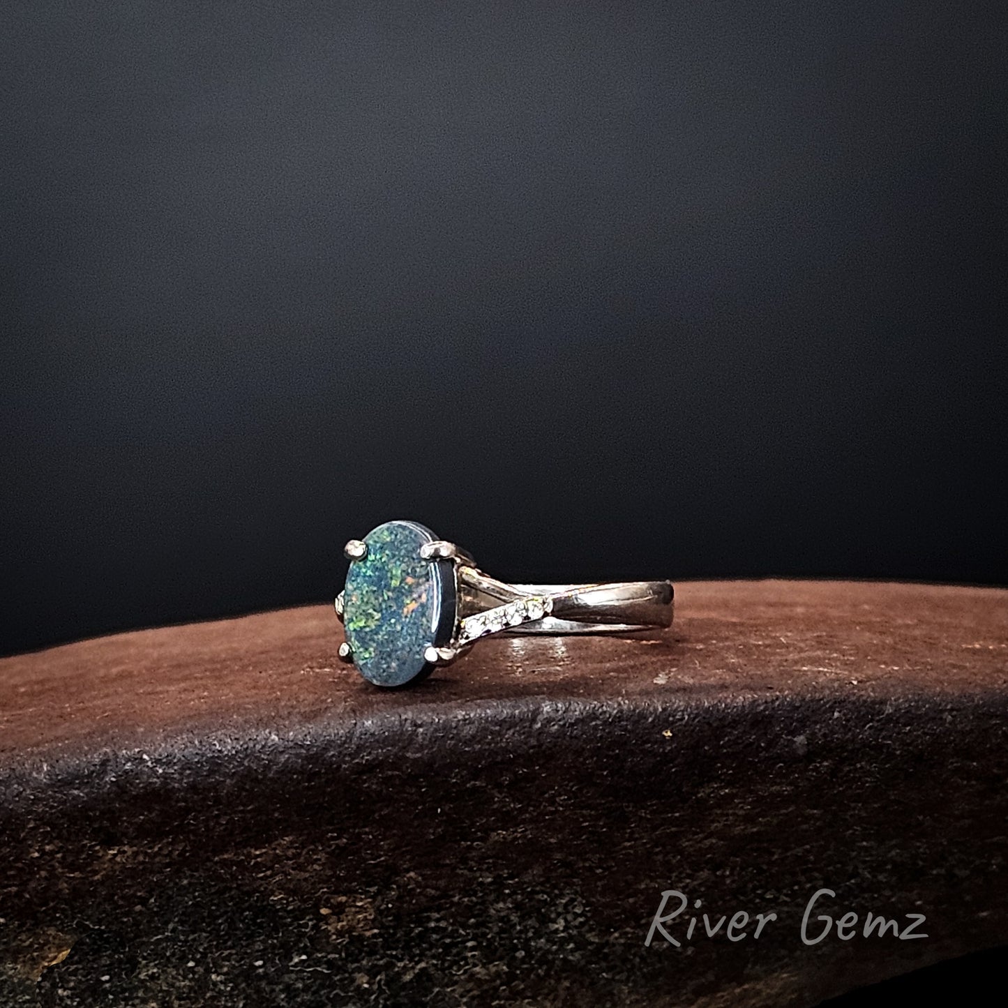 Multi-coloured black opal claw set in sterling silver ring with white topaz stone accents.